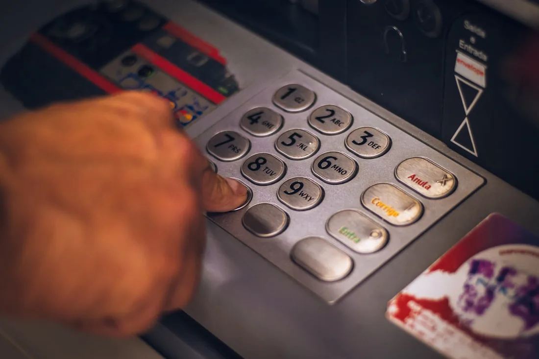 A hand entering a code on a cash machine