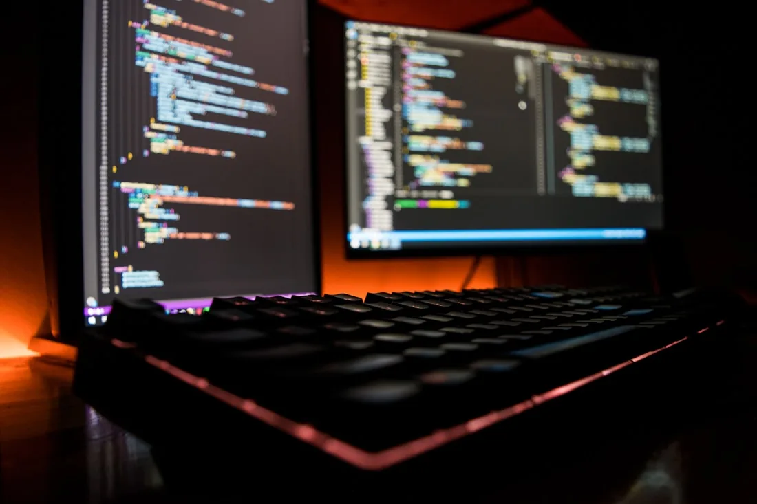 Code on a monitor above a backlit keyboard